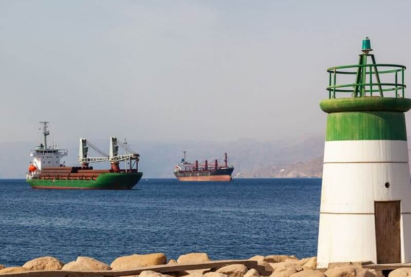 Cargo ships in the Red Sea with a small lighthouse on a shore